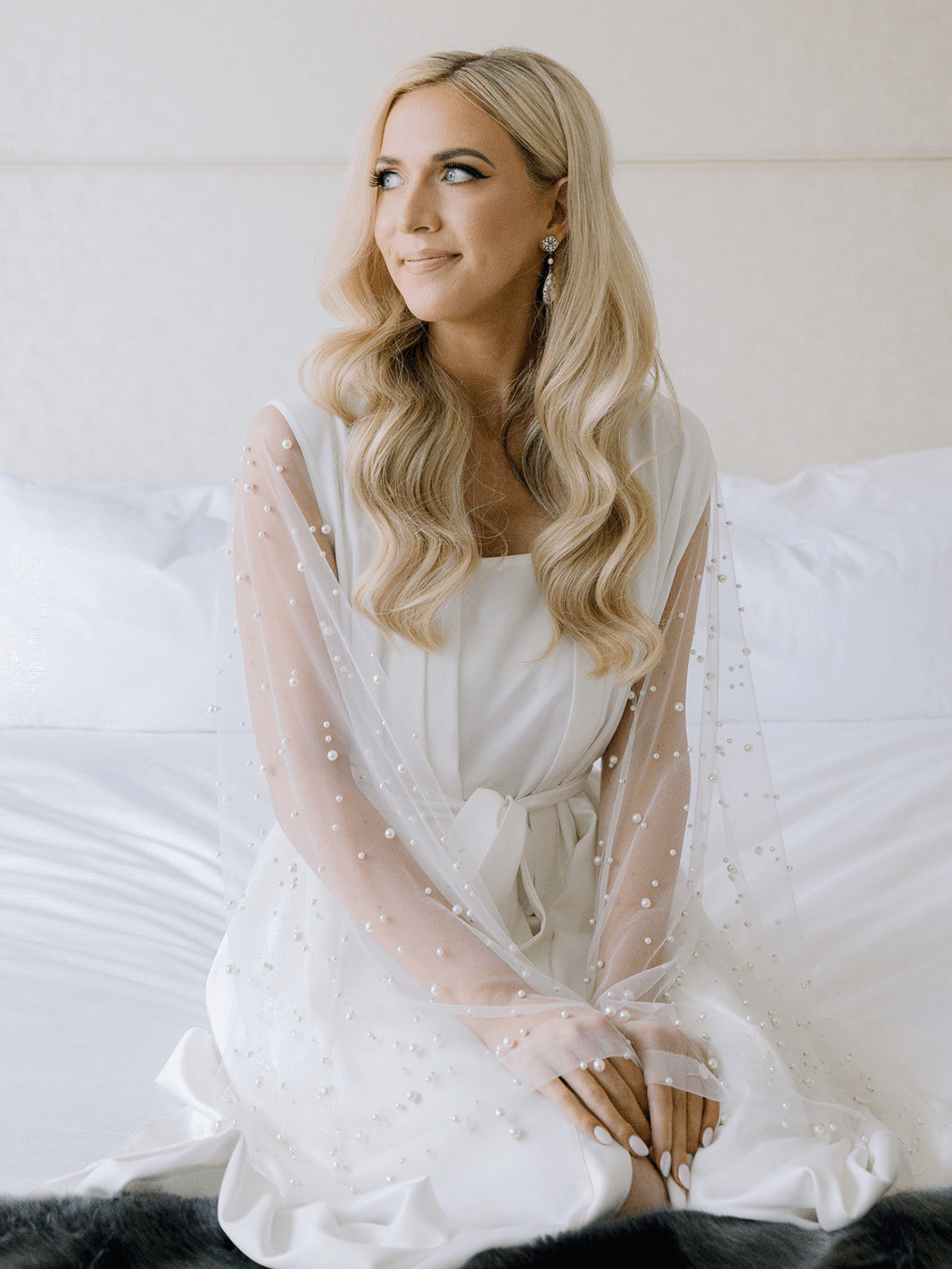 A side view of a medium-length wavy hairstyle held in place by two pearl-adorned hairclips