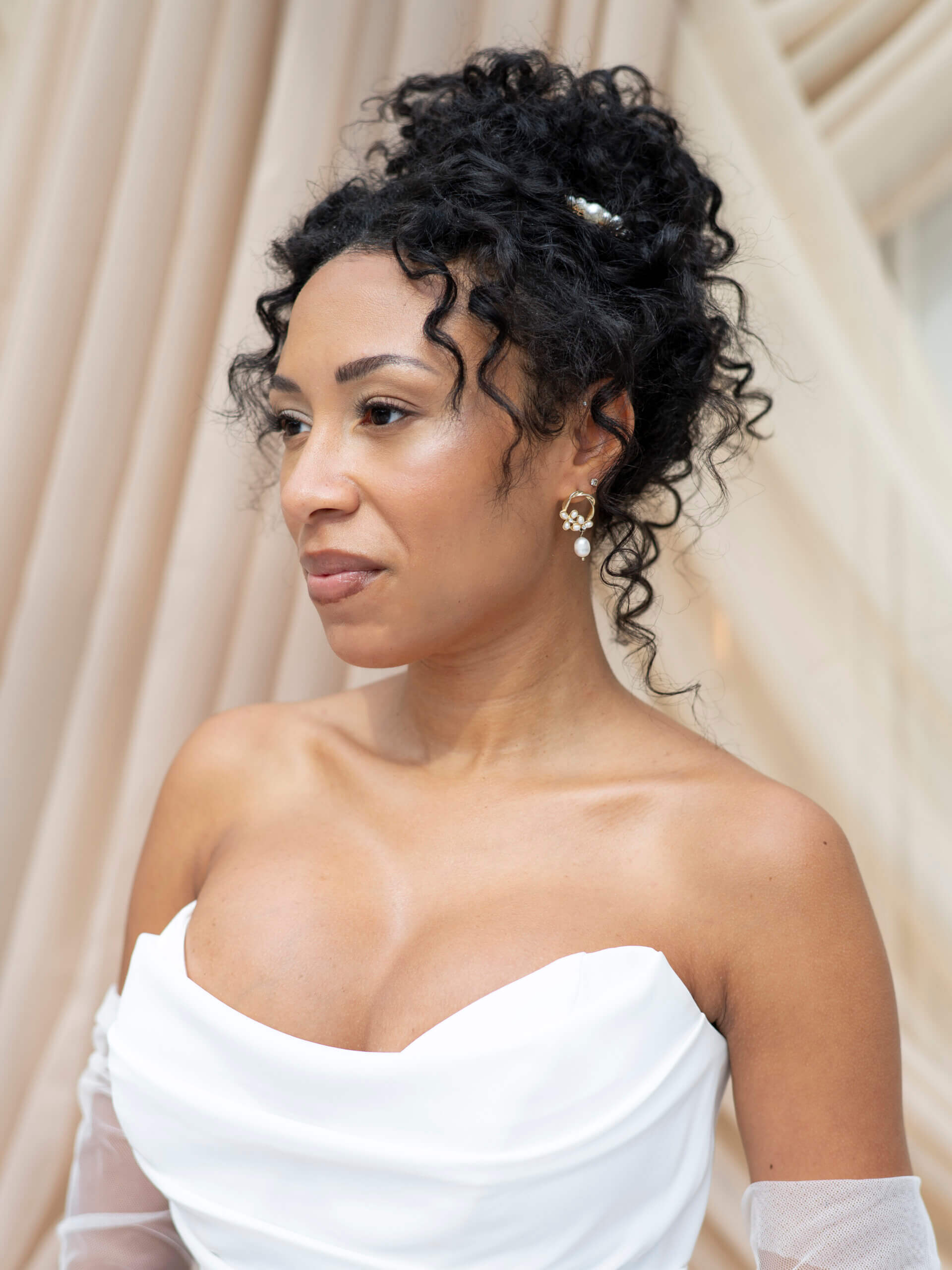 A side view of a medium-length wavy hairstyle held in place by two pearl-adorned hairclips