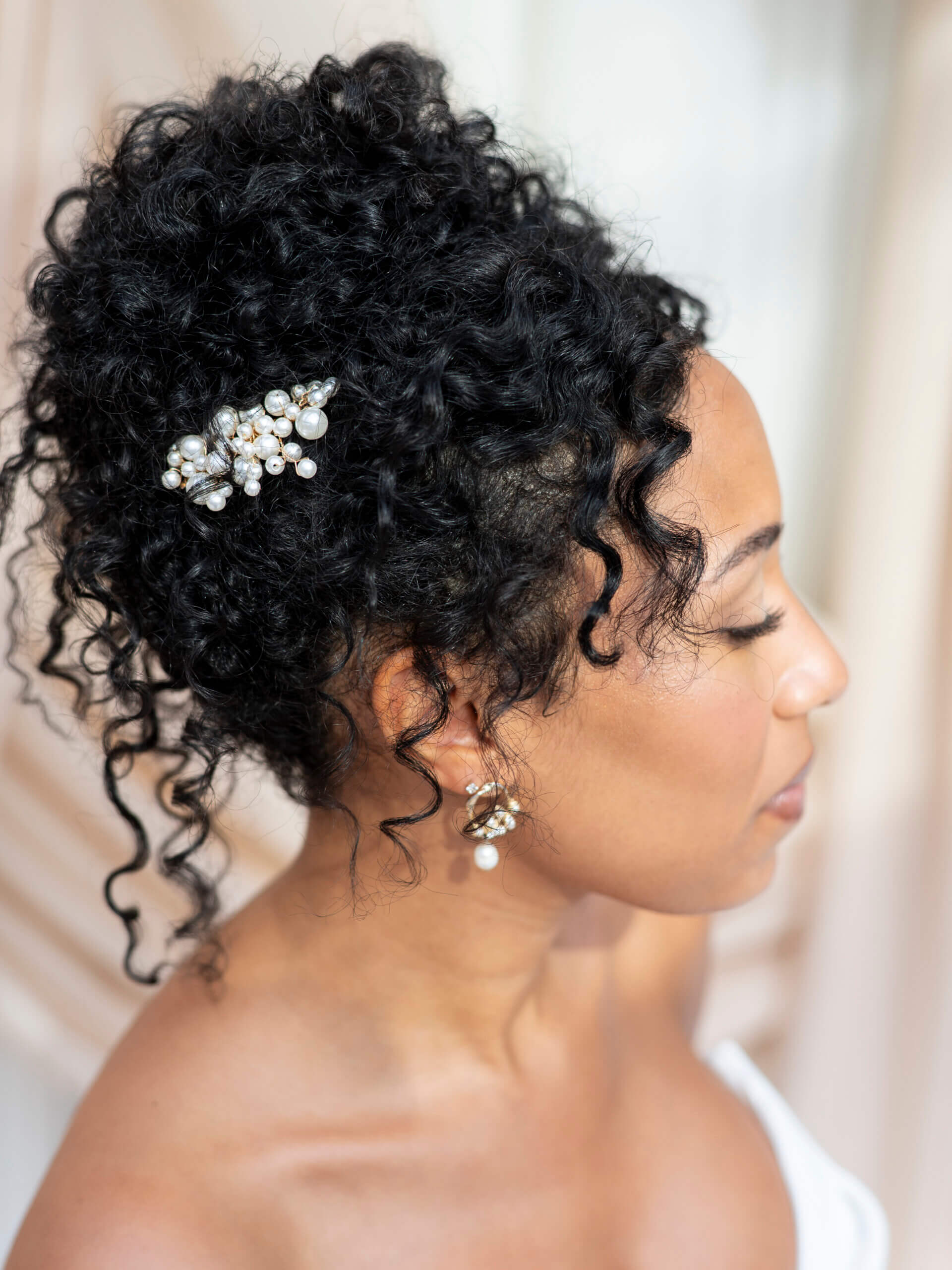 A three-quarters view of a medium-length wavy hairstyle held in place by two pearl-adorned hairclips